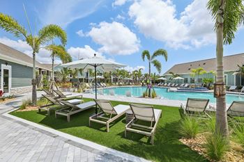 A poolside area with lounge chairs and palm trees.